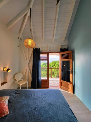 a bedroom with a bed and a sliding glass door at Bois Coco in Terre-de-Haut