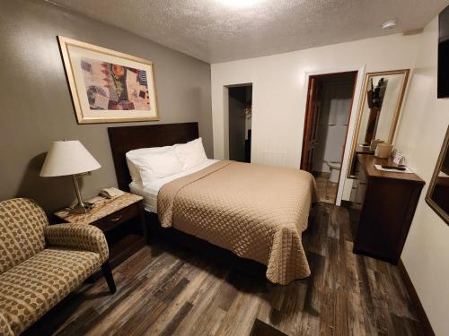 a bedroom with a bed and a couch and a chair at Jefferson Hills Motel in Clairton