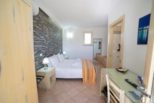 a bedroom with a white bed and a brick wall at Masseria Un Posto al Sole in Otranto