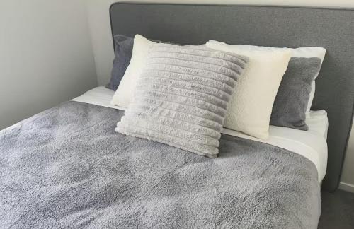 a bed with a gray blanket and pillows on it at Unit 3, 11 Hospital Road Apartment in Wellington