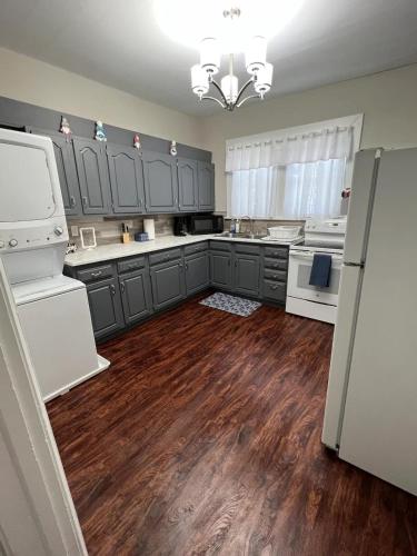 a large kitchen with gray cabinets and wooden floors at The Modern Victorian in Uniontown