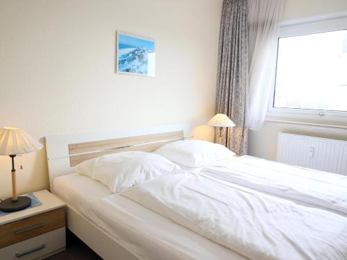 ein weißes Bett in einem Schlafzimmer mit einem Fenster in der Unterkunft Gemütliches 2-Zimmer-Appartement mit Balkon. in Westerland