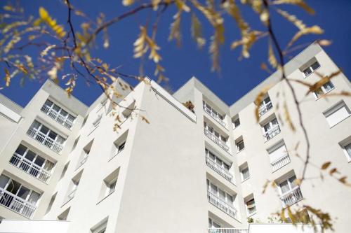 un immeuble d'appartements blanc avec un ciel bleu dans l'établissement une chambre privee entre paris et disneyland, à Noisy-le-Grand