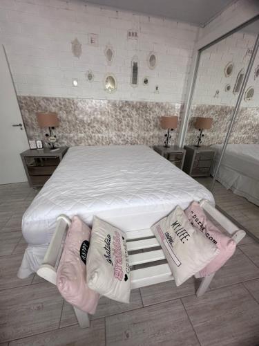 Una cama blanca con tres almohadas encima. en Casa em Bombas, en Bombinhas