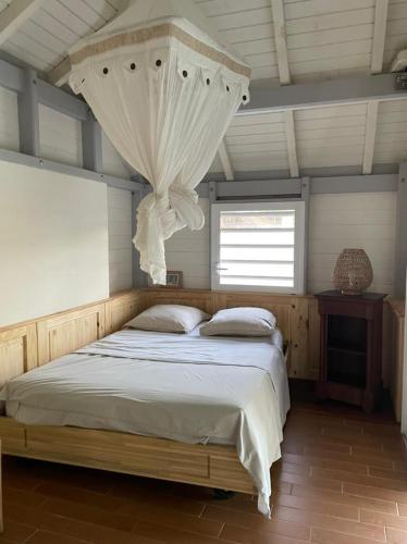 a bedroom with a large bed with a curtain above it at KER MARYA Bungalow in Terre-de-Haut
