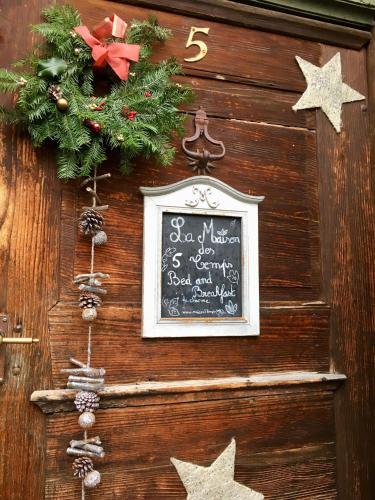 a chalkboard with a christmas wreath on a wooden wall at B&B de charme La Maison des 5 Temps in Ferrette