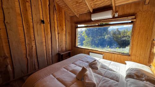 ein Schlafzimmer mit einem Bett in einem Zimmer mit einem Fenster in der Unterkunft Hotel Conguillío in Melipeuco