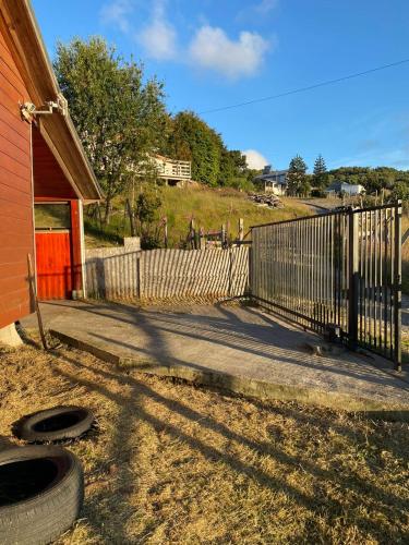 a fence next to a house with a tire next to it at Cabaña 2 pisos in Natri