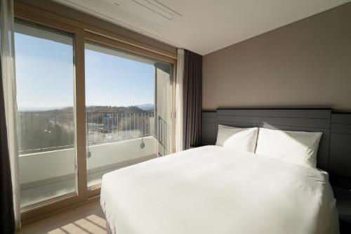 a bedroom with a white bed and a large window at Hotel The Blue Terra in Sokcho