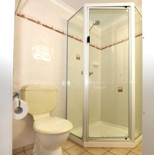 a bathroom with a toilet and a glass shower at Horizons 3a in Bargara