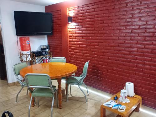 a room with a table and chairs and a red brick wall at Duplexsanber in San Bernardo