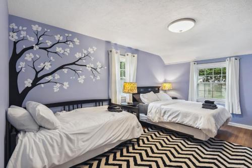 a bedroom with two beds and a tree mural at The Henry House I Pet Friendly Cozy Convenient in Fairview Park