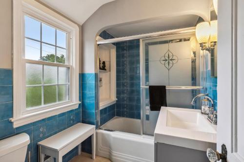 a blue tiled bathroom with a tub and a sink at The Henry House I Pet Friendly Cozy Convenient in Fairview Park