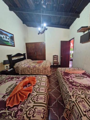 a room with three beds and a ceiling at Hospedaje El Viajero Antigua llI in Antigua Guatemala