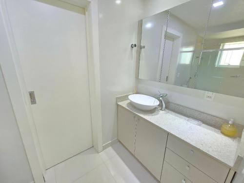 a white bathroom with a sink and a mirror at APT 804 - Brava Beach - 3 Quartos - 2 Vagas Garagem in Cabeçudas