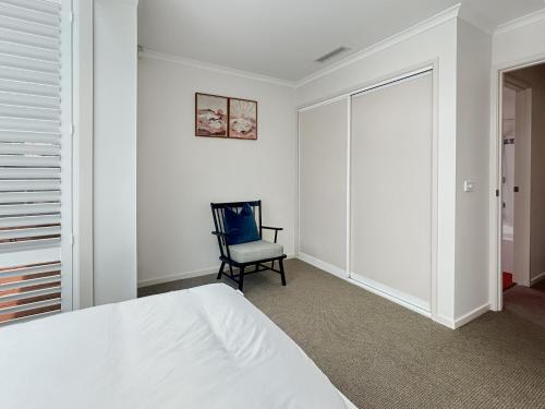 a white bedroom with a bed and a chair at Spacious 4-Bed Home with Coastal Charm in Long Beach
