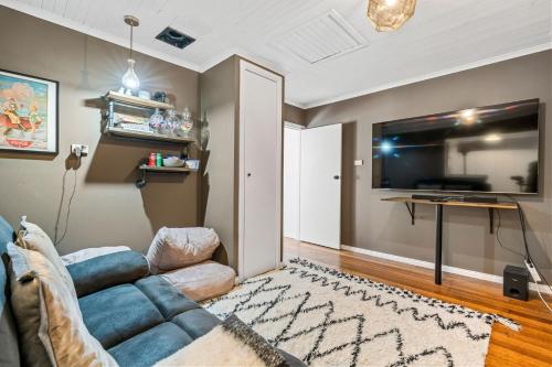a living room with a couch and a flat screen tv at Stargazers Waterfront Hot tub Cottage Tasmania in Clarence Point
