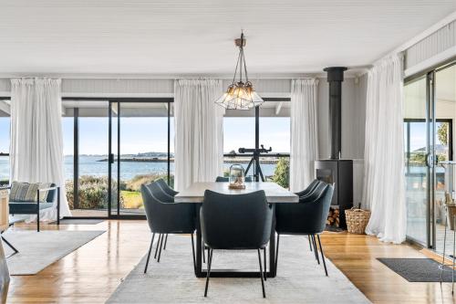 a dining room with a table and chairs with a view at Stargazers Waterfront Hot tub Cottage Tasmania in Clarence Point