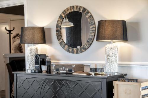 deux lampes au-dessus d'une commode avec miroir dans l'établissement Stargazers Waterfront Hot tub Cottage Tasmania, à Clarence Point