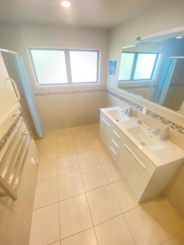 a white bathroom with a sink and a mirror at Mangonui Ridge Retreat in Mangonui