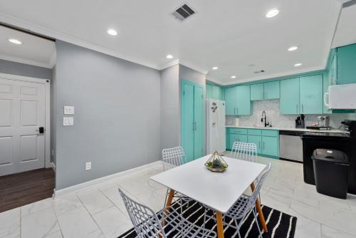 a kitchen with blue cabinets and a white table and chairs at Spacious 2BR Apt with King Beds & Fully Equipped Kitchen in Houston