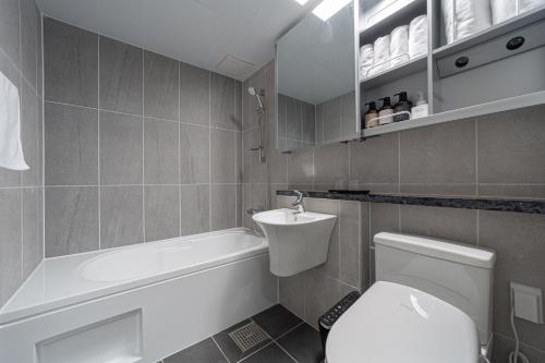 a bathroom with a toilet and a tub and a sink at Bella Stay in Chuncheon