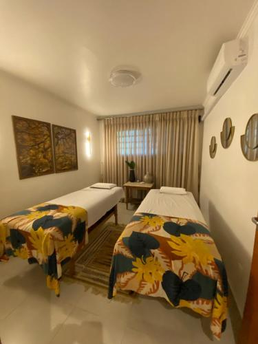 a bedroom with two beds and a table and a window at Spa orgânico chalé dos Ipês in Jundiaí
