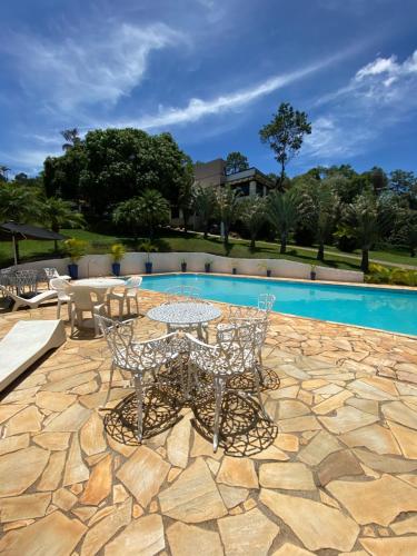 a patio with a table and chairs next to a pool at Spa orgânico chalé dos Ipês in Jundiaí