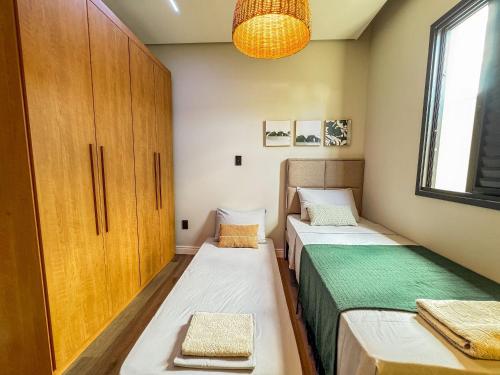 zwei Betten in einem kleinen Zimmer mit Fenster in der Unterkunft Casa Bela - Centro in Águas de Lindóia