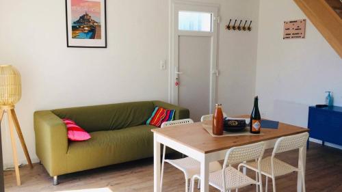 a living room with a green couch and a table at Jacuzzi & Sauna privatifs - Vue mer in Blainville-sur-Mer