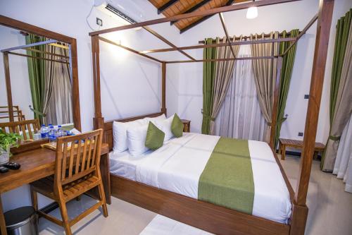a bedroom with a bed and a table and a desk at Villa Freedom in Hikkaduwa