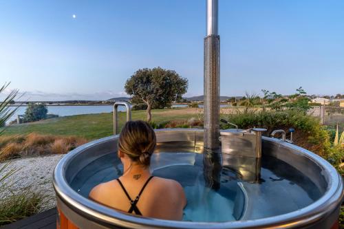 a woman in a jacuzzi tub with a view at Stargazers Waterfront Hot tub Cottage Tasmania in Clarence Point