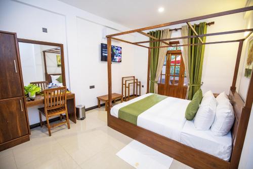 a bedroom with a bed and a desk in a room at Villa Freedom in Hikkaduwa