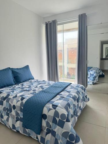 a blue and white bed in a room with a window at Casa brisa do mar 2 in Arraial do Cabo
