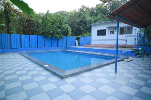 a swimming pool in a yard with a blue fence at Anand hillside Retreat 3BR Pool Villa by Homeyhuts in Māndvi