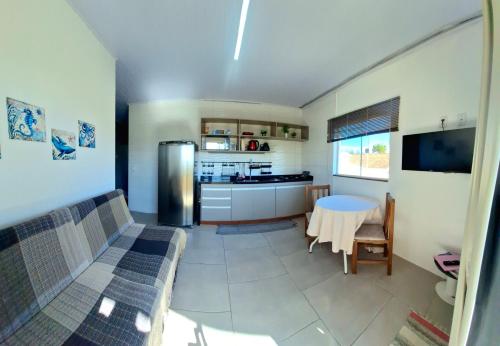 a kitchen and living room with a table and a refrigerator at Kitnet em Imbituba - Fabi in Imbituba