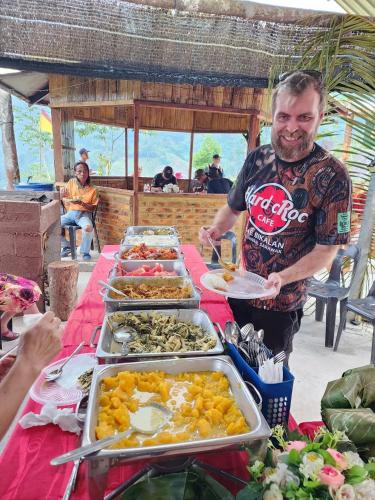 a man standing in front of a table of food at Baruk Mas Kampung Assum in Kuching