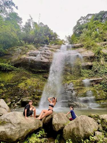 three people sitting on rocks in front of a waterfall at Baruk Mas Kampung Assum in Kuching