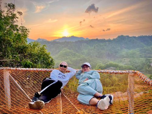 two people sitting on a hammock with the sunset in the background at Baruk Mas Kampung Assum in Kuching