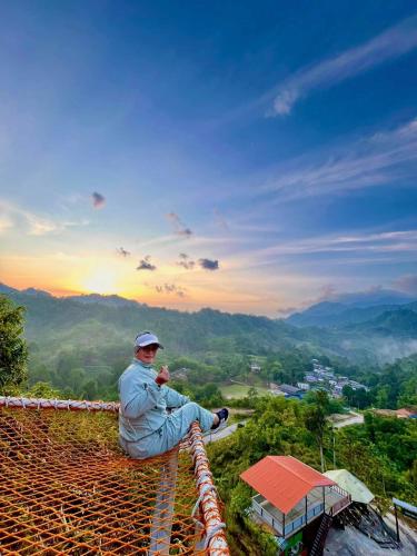 a man sitting on the edge of a roof at Baruk Mas Kampung Assum in Kuching