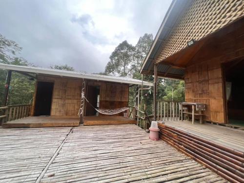 a porch of a wooden house with a hammock on it at Baruk Mas Kampung Assum in Kuching