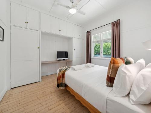 a white bedroom with a large bed and a window at Westlee Cottage in Wentworth Falls