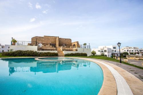 a large blue swimming pool with buildings in the background at Golden Carthage Residences in Gammarth