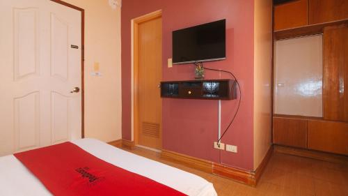 a room with a bed and a tv on a wall at RedDoorz @ Farm Side Hotel Laoag City in Laoag