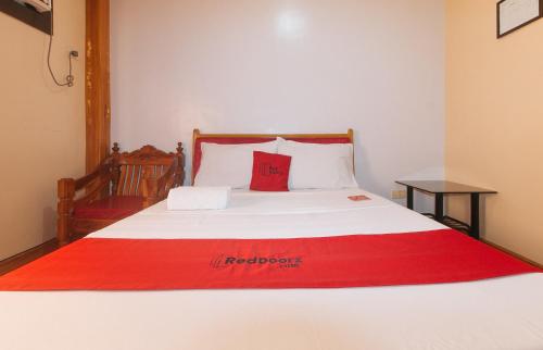a bed with a red blanket on top of it at RedDoorz @ Farm Side Hotel Laoag City in Laoag