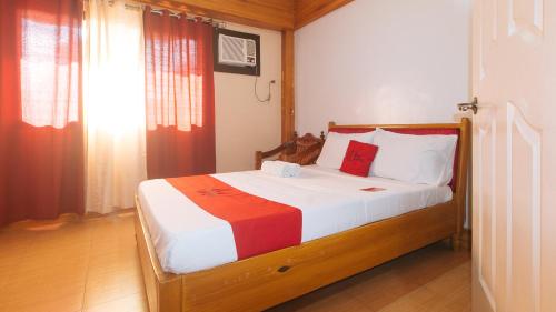 a bedroom with a bed with red and white sheets at RedDoorz @ Farm Side Hotel Laoag City in Laoag