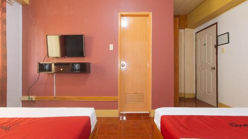 a room with two beds and a tv on a wall at RedDoorz @ Farm Side Hotel Laoag City in Laoag