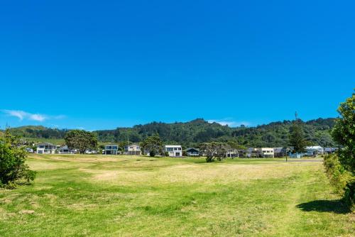 a large grassy field with houses in the background at Sun, Sand, Serenity - Waihi Beach Holiday Home in Waihi Beach