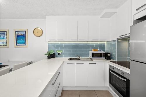 a kitchen with white cabinets and blue tiles at Surfers Paradise- meters from the beach! in Gold Coast
