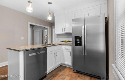 a kitchen with a stainless steel refrigerator and white cabinets at Riverside Craftsman with 3 beds and 3 baths, Pet friendly, Great neighborhood in Jacksonville
